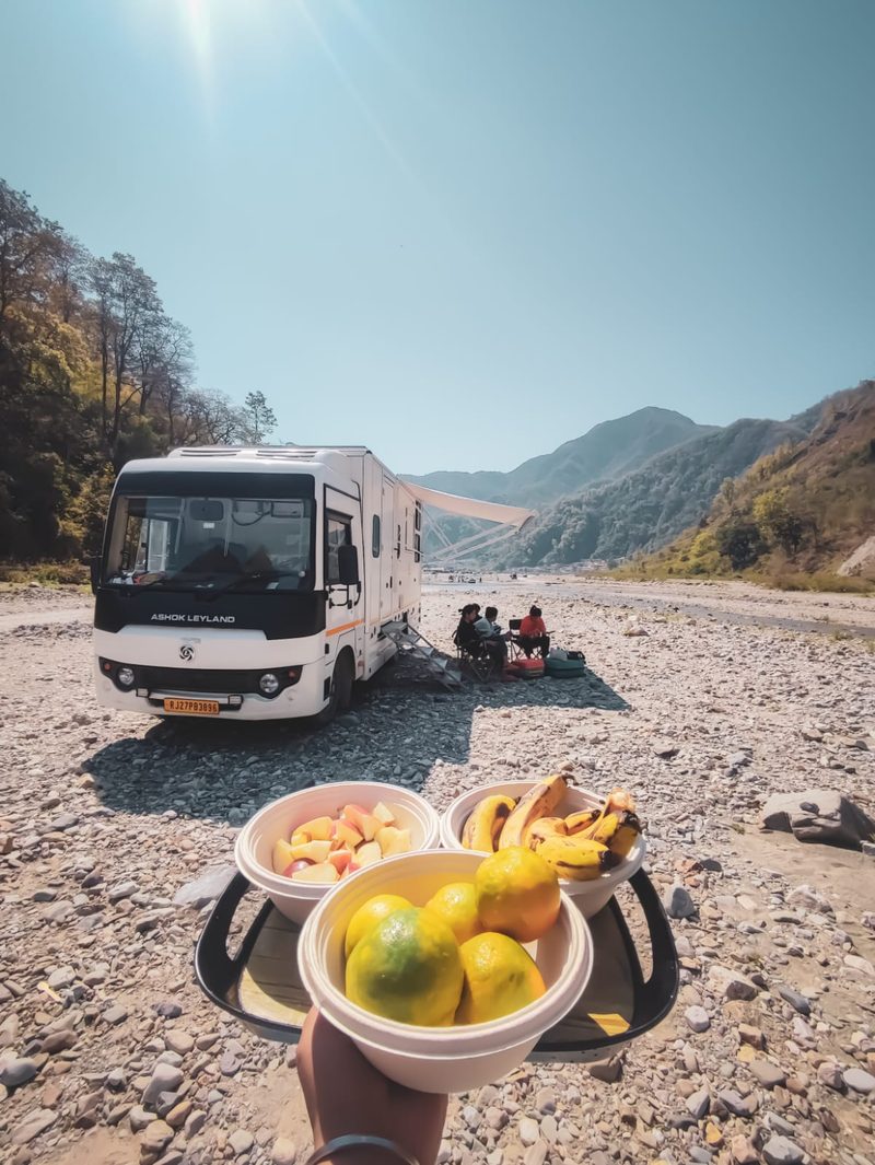 Family relaxing by a river beside the caravan